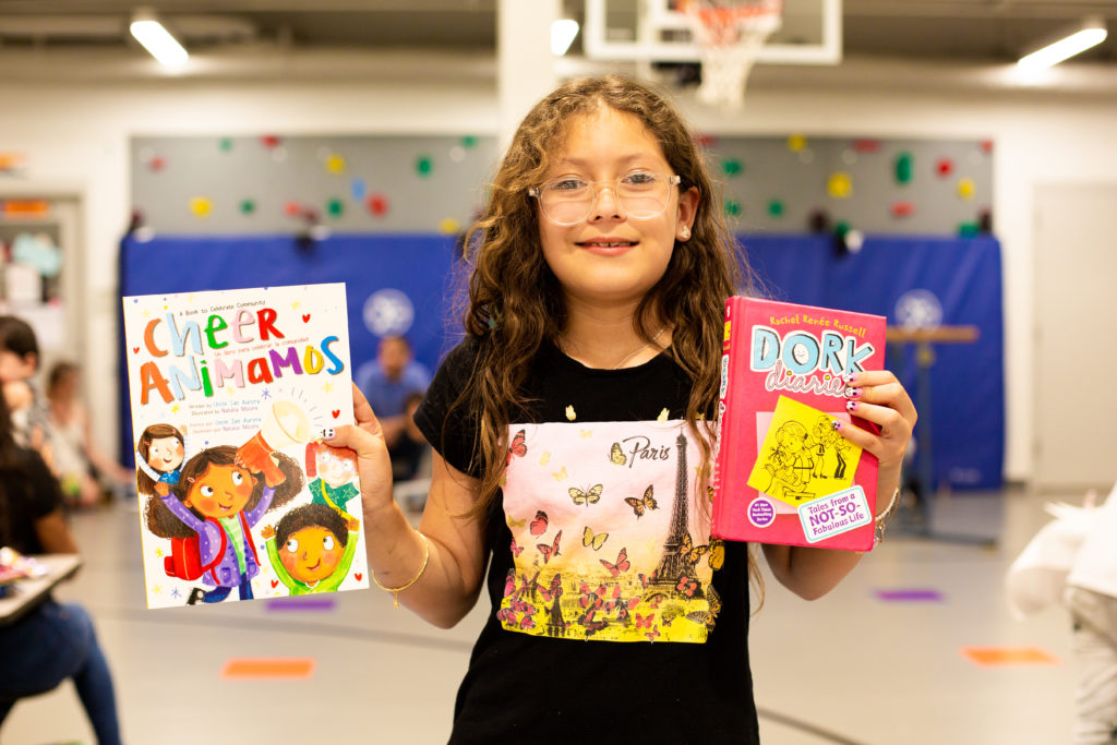 Photo of young girl wearing a black shirt and holding two books at the Family Literacy Night.