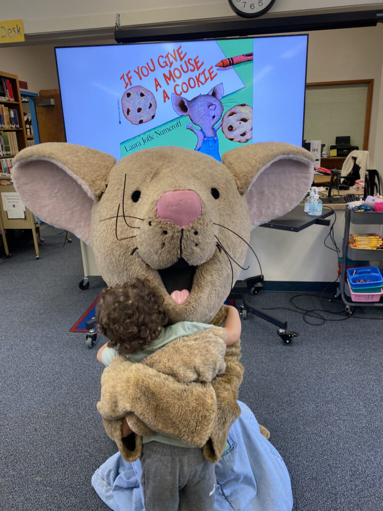 A child hugs a mouse mascot 