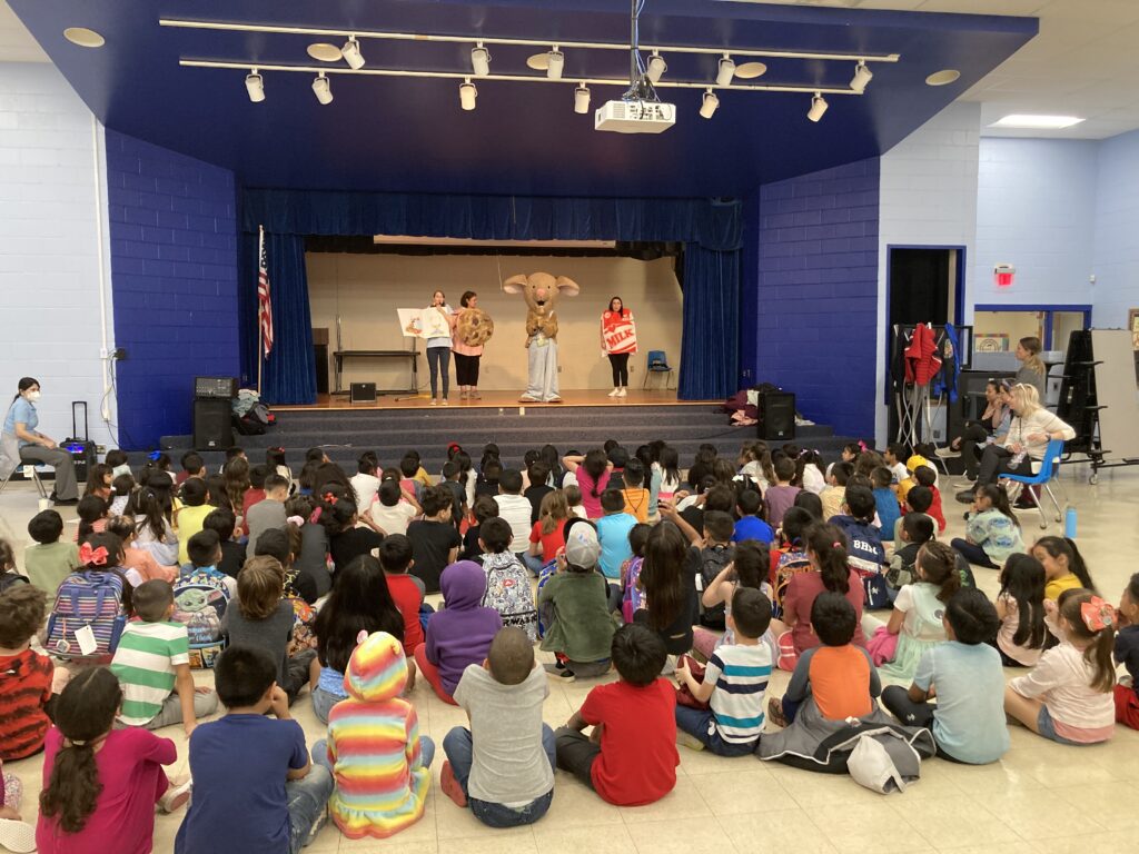 Kids sit around a stage and watch a performance